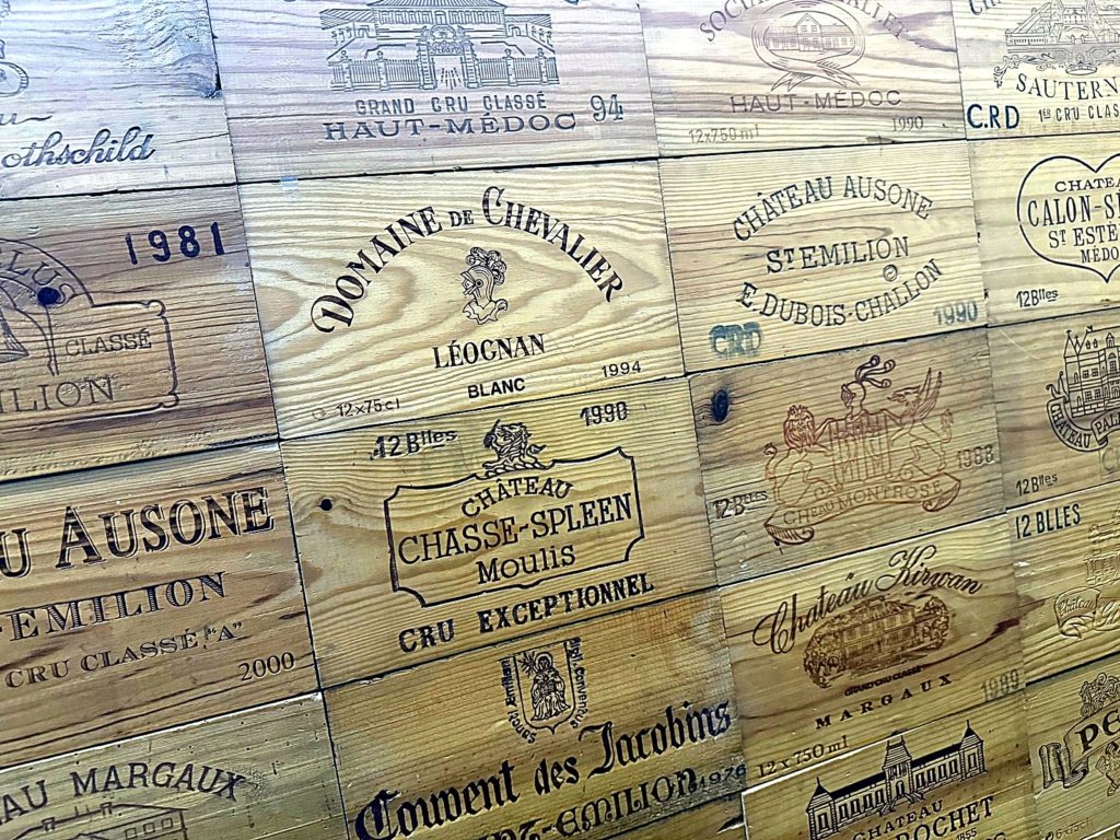 Mur de caisses de grands crus chez Maison Busquets : Château Ausone, Domaine de Chevalier, Chasse-Spleen