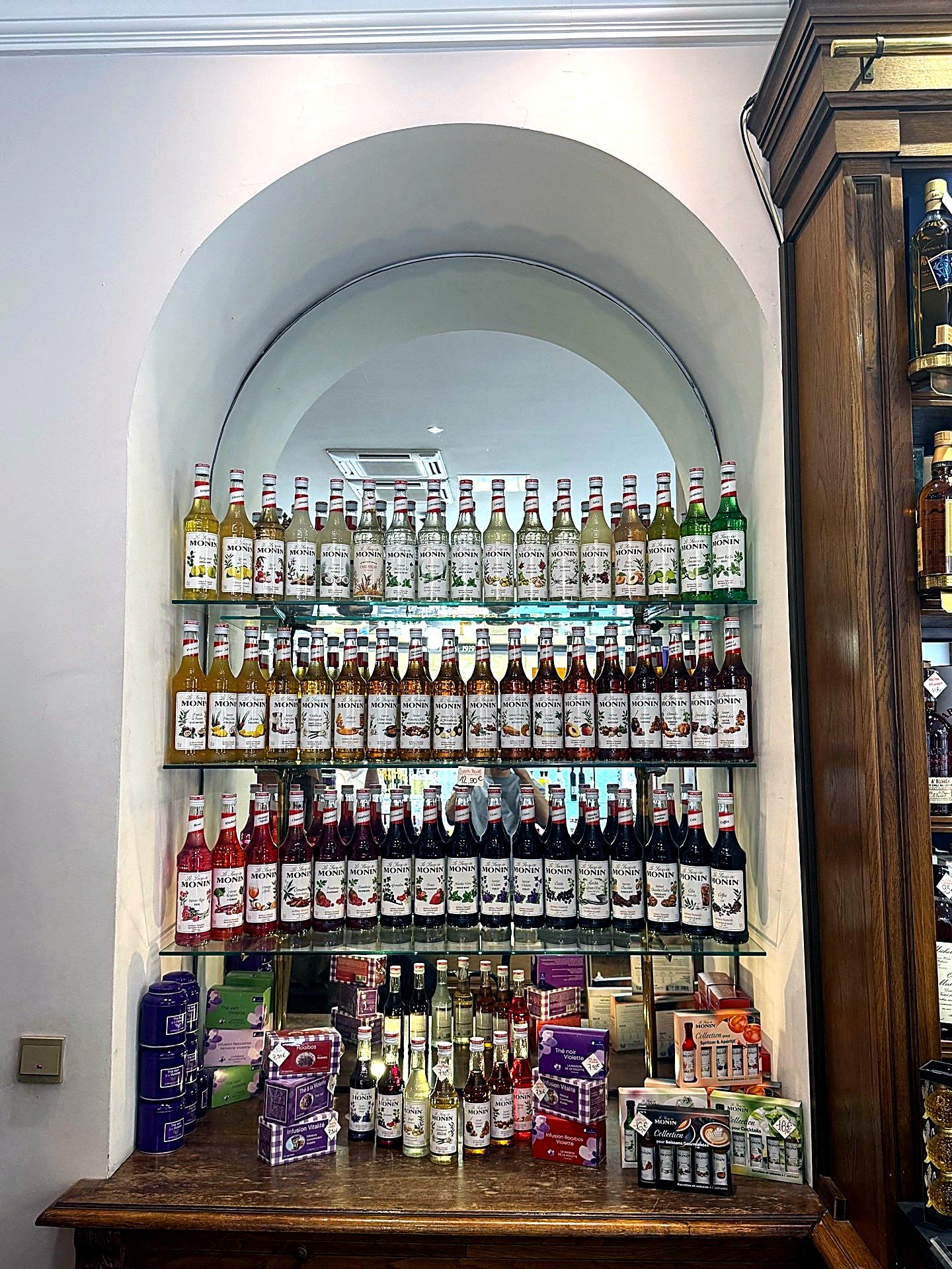 Niche murale garnie de sirops Monin en trois rangées de couleurs, boutique Victor Hugo, Maison Busquets