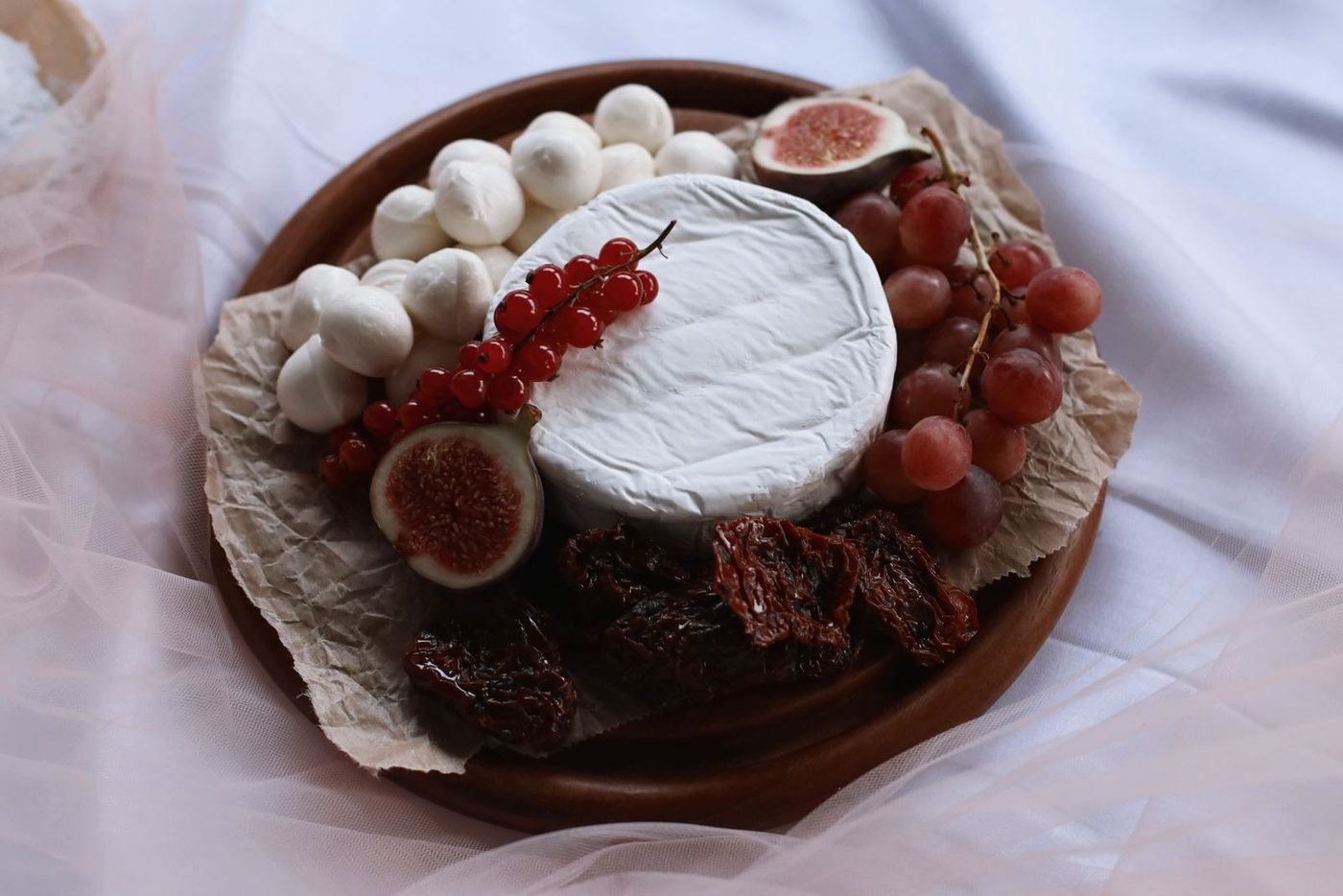 Fromage à pâte molle à croûte fleurie entier, figues et raisin sur un plateau
