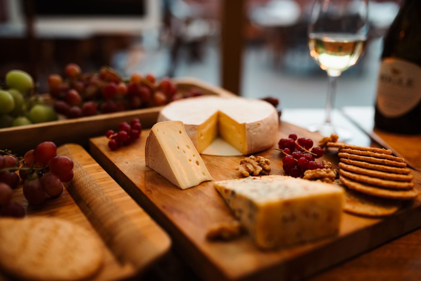 Planche de fromages variés avec raisin, noix et un verre de vin blanc