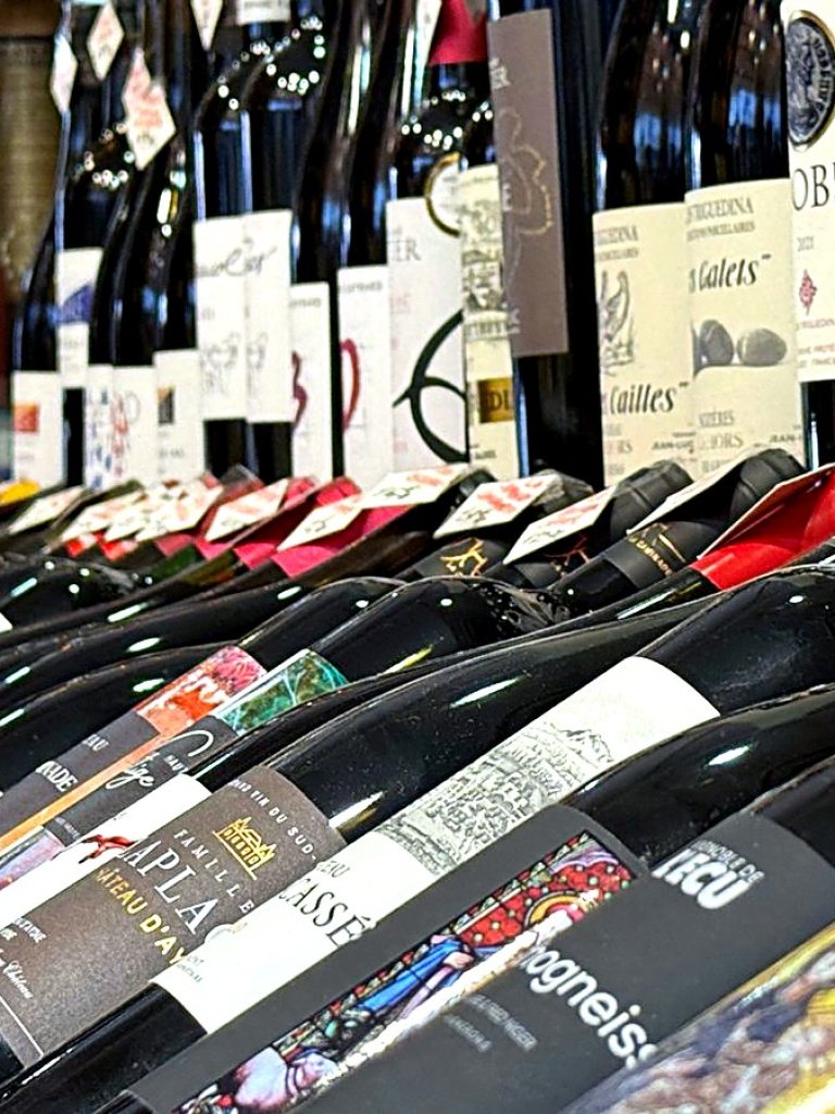 Bouteilles de vin debout sur les étagères de la cave à vin Busquets à Toulouse, prix affichés